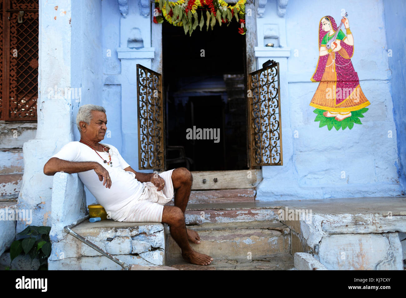 Alte indische Mann in Weiß gekleidet sittingon die Treppe vor seinem Haus, Jodhpur, Rajasthan, Indien. Stockfoto