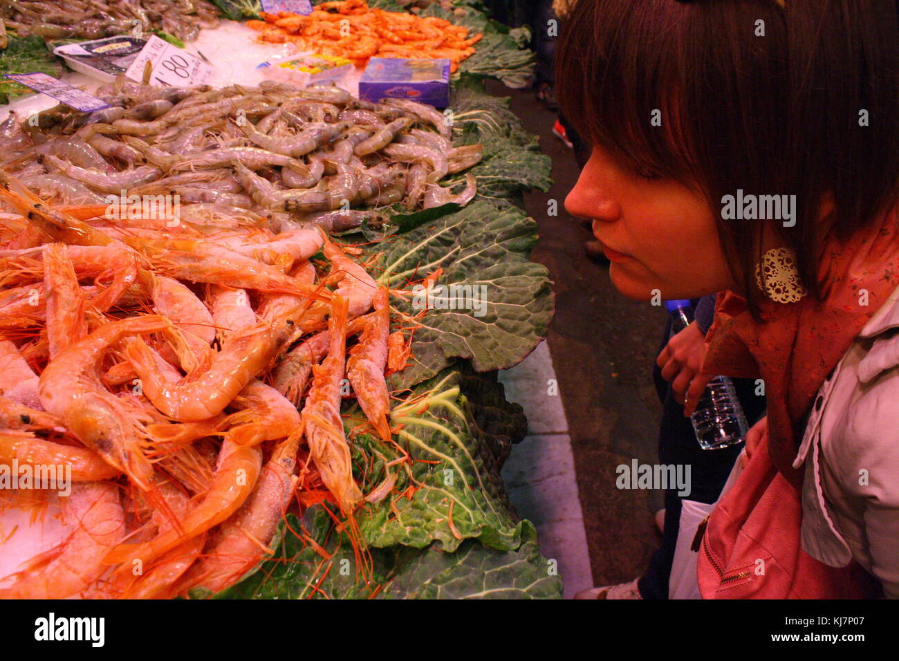 Ein Mädchen sieht und riecht die frische Garnelen auf dem Fischmarkt. Stockfoto
