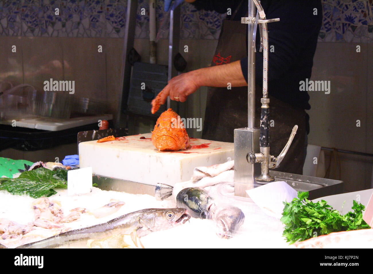 Ein Lebensmittelmarkt Verkäufer schneidet einen frisch gefangenen Fisch zum Essen zu verkaufen. Stockfoto