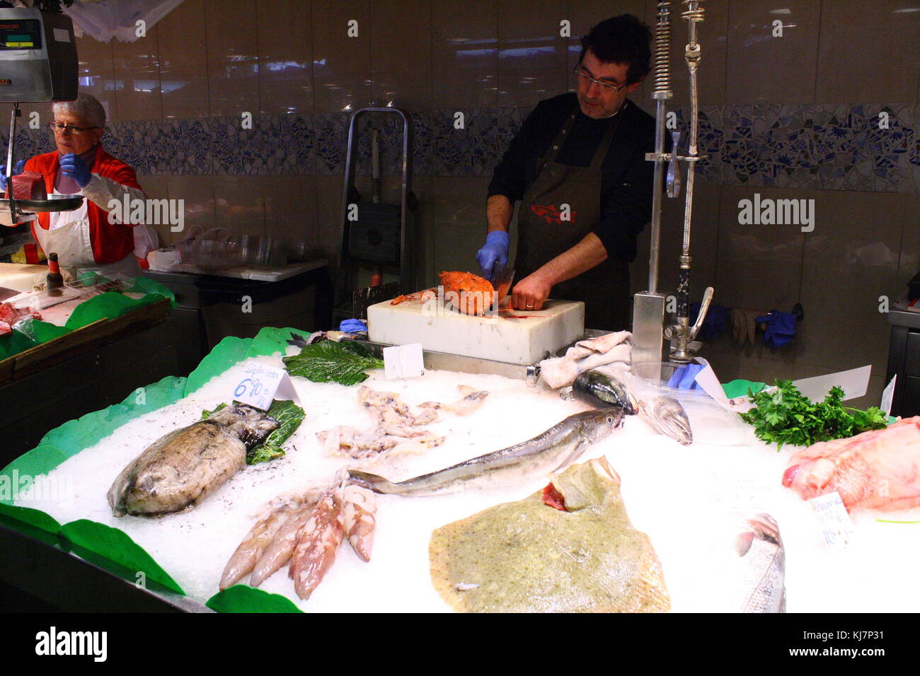 Ein Lebensmittelmarkt Verkäufer schneidet einen frisch gefangenen Fisch zum Essen zu verkaufen. Stockfoto