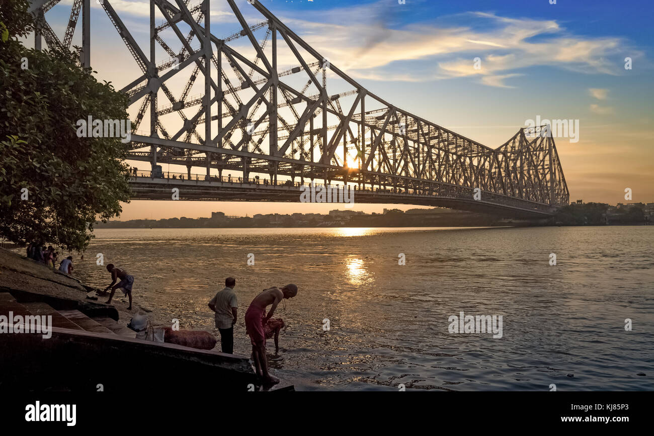 Howrah Bridge Kalkutta bei Sonnenaufgang mit Menschen baden am Ganges River Bank Stockfoto