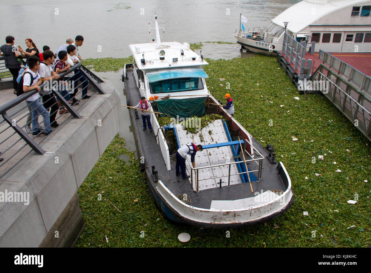 Ein Boot säubert das Wasser in der Nähe des Bund in den Fluss Huangpu in Shanghai, China. Stockfoto