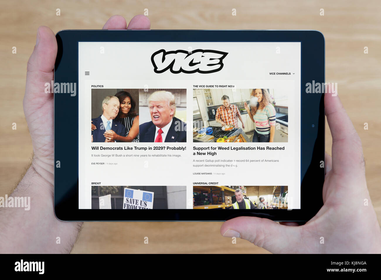 Ein Mann sieht der stellvertretende Website auf seinem iPad tablet device, Schuß gegen einen hölzernen Tisch top Hintergrund (nur redaktionelle Nutzung) Stockfoto