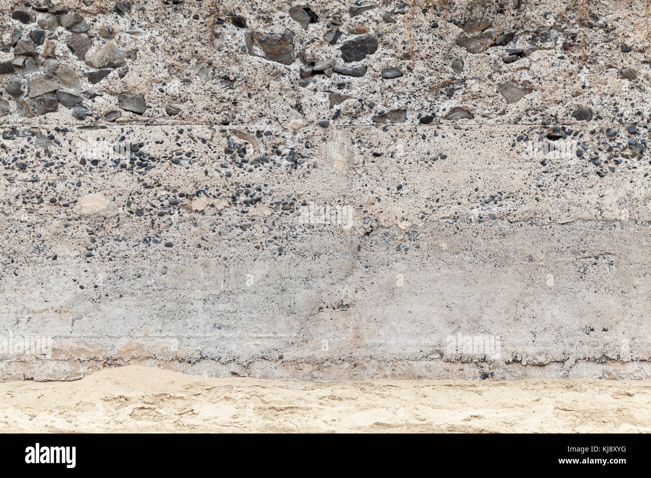 Rauen Beton Wand mit Steinen und sandigen Boden, leeren Innenraum Hintergrund Foto Textur Stockfoto