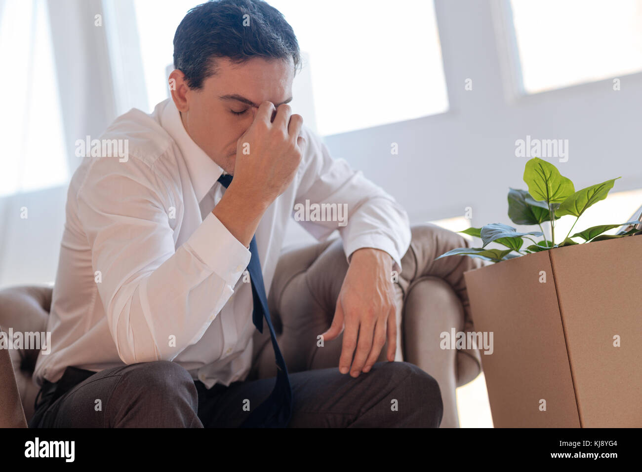 Traurige Mann sitzt mit geschlossenen Augen, während mit einer Kopfschmerzen erschöpft Stockfoto