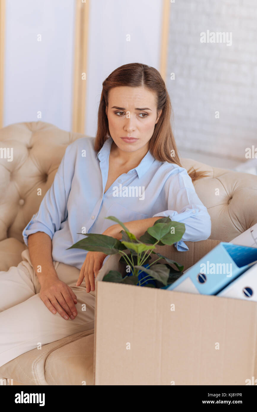 Verärgert junge Frau zu Hause sitzt nach, ihren Job zu verlieren. Stockfoto