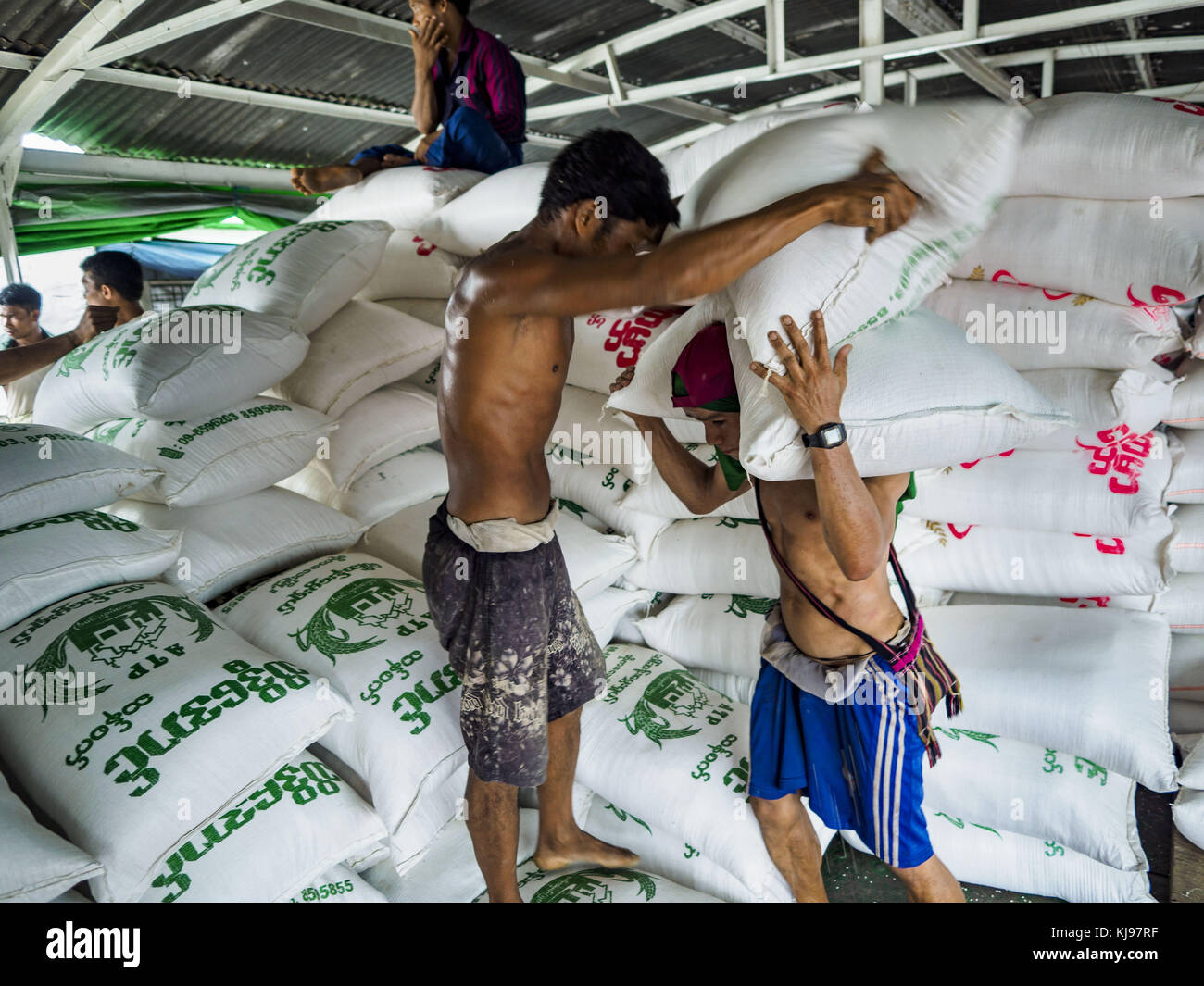 Yangon, Region Yangon, Myanmar. November 2017. Stevedores entladen eine Ladung Reis von einem Lastkahn, der am Twante-Kanal in Yangon angedockt ist. Myanmars Straßennetz liegt seinen Nachbarn in Südostasien hinterher, und noch immer wird viel Fracht von Schiffen und Lastkähnen bewegt. Von hier aus wird Reis in Exportqualität umverpackt und nach Übersee verschickt, und Reis für den Inlandsverbrauch wird in andere Städte Myanmars verschickt. Quelle: Jack Kurtz/ZUMA Wire/Alamy Live News Stockfoto