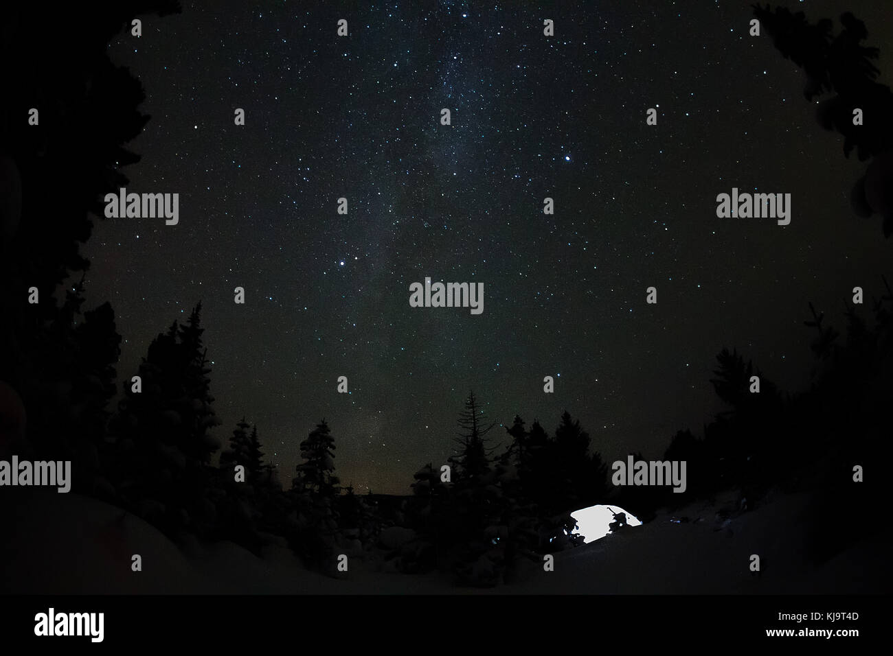 Weiße Zelt unter dem Sternenhimmel und die Milchstraße in die Bäume im Winter Berge bei Nacht. Stockfoto