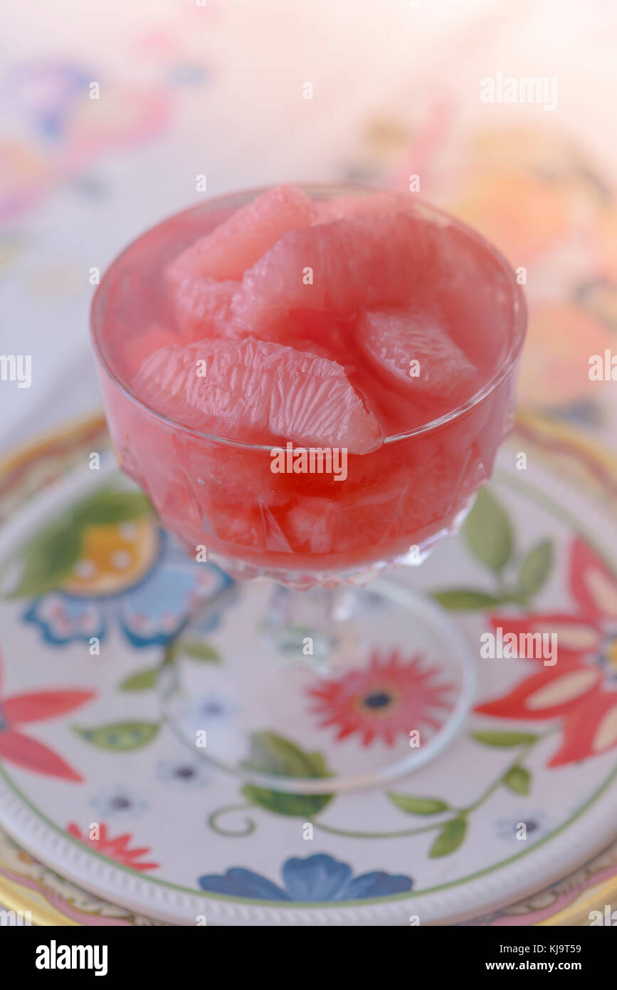 Rosa Grapefruit in einem Glas Kompott mit bunten Platte Stockfoto