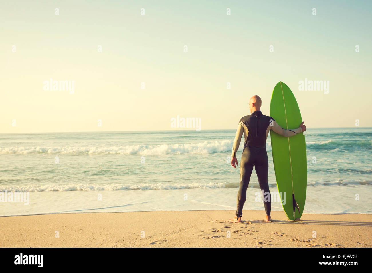 Surfer am Strand Holding ist surfboaerd und beobachten die Wellen Stockfoto