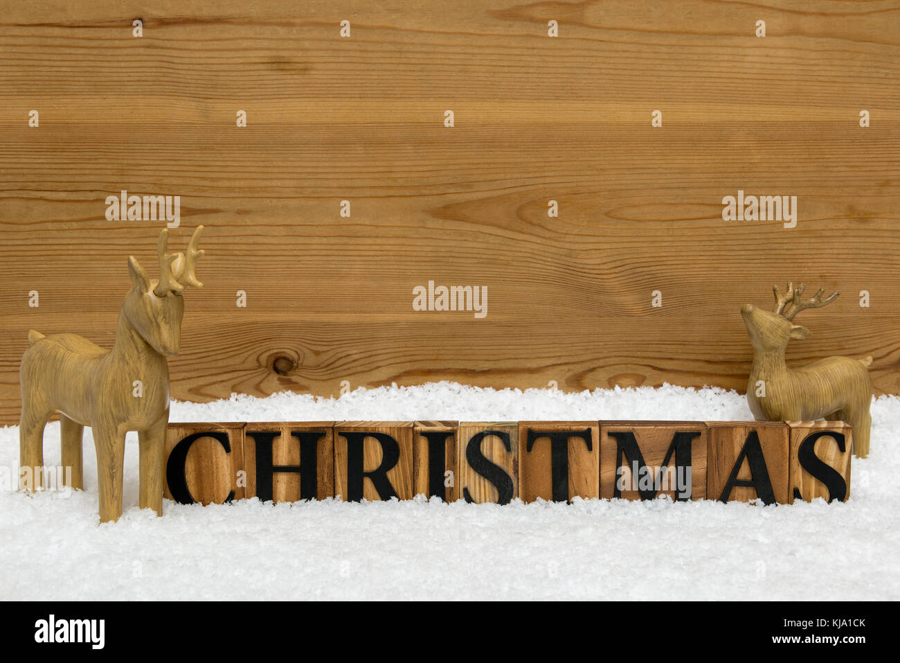 Das Wort Weihnachten mit zwei hölzernen Rentiere im Schnee, kopieren Sie Raum für Ihre eigene Nachricht. Stockfoto