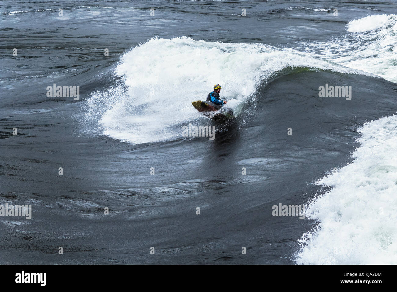 Ein Playboater surft sein Kajak auf dem Gesicht von einer riesigen Welle in Sechelt Rapids (skookumchuck), eine der höchsten Gezeiten der Welt vergeht (British Columbia). Stockfoto
