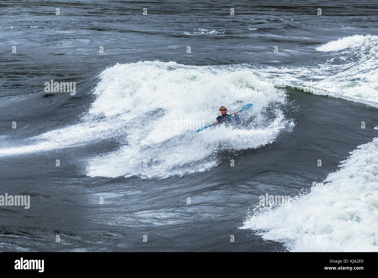 Ein Playboater und sein Kajak fast verschwinden unter dem Schaumstoff von einer riesigen Welle in Sechelt Rapids (kookumchuck'), eine der schnellsten Gezeiten der Welt vor sich geht. Stockfoto