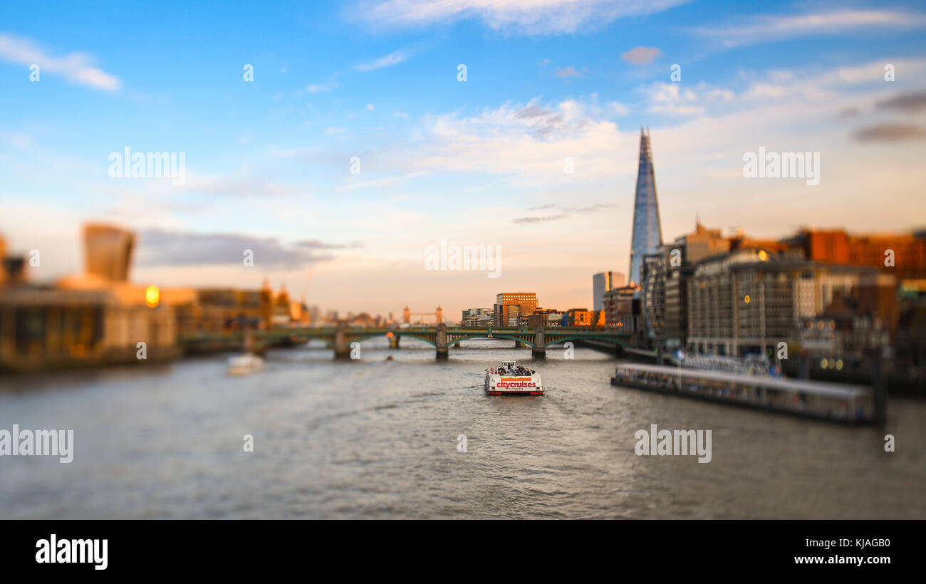 Anzeigen von Millennium Fußgängerbrücke in Richtung der Shard und Tower Bridge mit City Cruises Yacht Passing auf der Themse. Mit Tilt Shift Effekt. Stockfoto