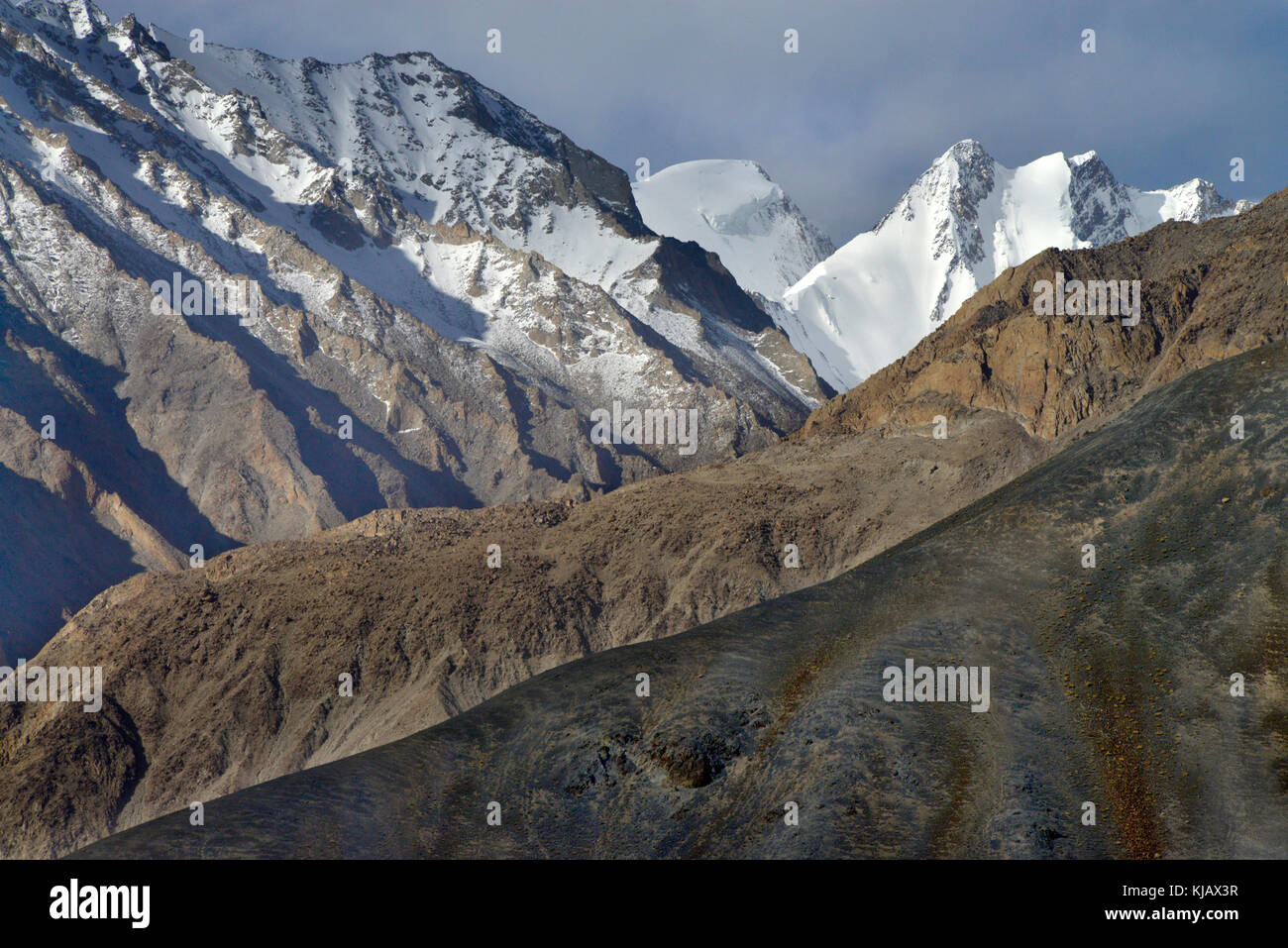 Hohe Berge, Gletscher: Snowy scharfen Spitzen, bedeckt mit ewigem Eis, im Vordergrund schneidende braun Pisten. Stockfoto