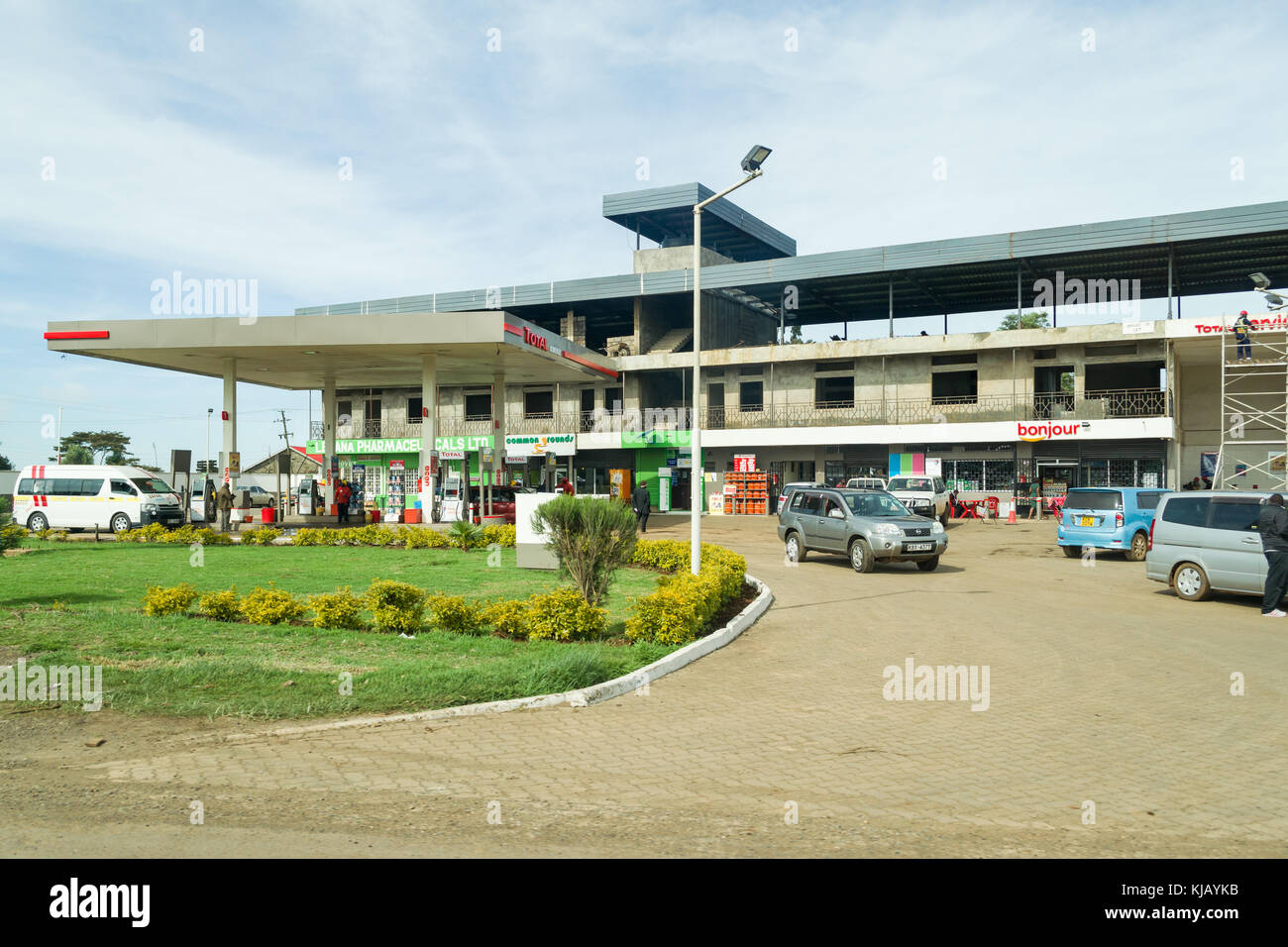 Eine Total Tankstelle mit im Bau befindlichen Gebäude dahinter und Kunden und Fahrzeuge auf dem Vorplatz, Kenia, Ostafrika Stockfoto