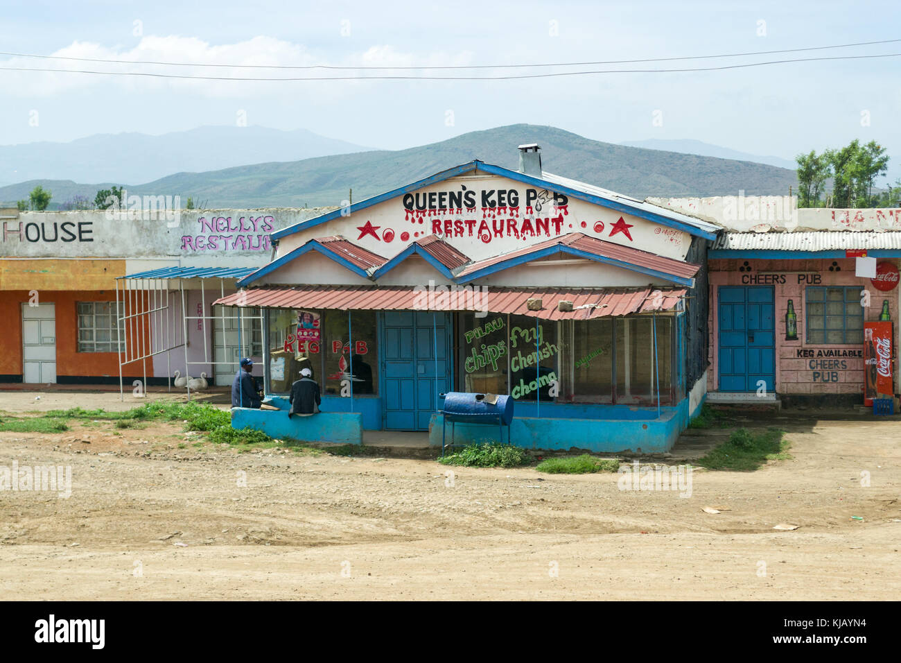 Zwei afrikanische Männer sitzen draußen ein kleines Restaurant und andere Geschäfte, Kenia, Ostafrika Stockfoto