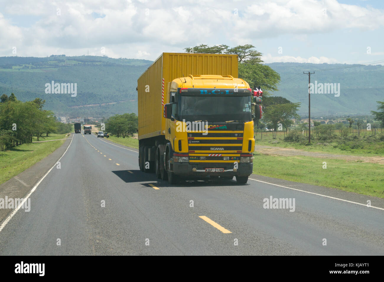 Ein gelbes Fahrzeug fährt entlang der alten Straße von Naivasha, Kenia, Ostafrika Stockfoto