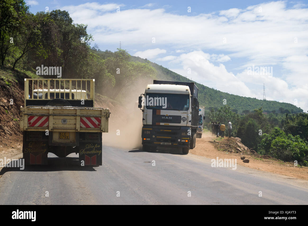 Lkw Fahren auf einer staubigen Straße durch das Rift Valley Böschung mit Menschen standen am Straßenrand, Kenia, Ostafrika Stockfoto