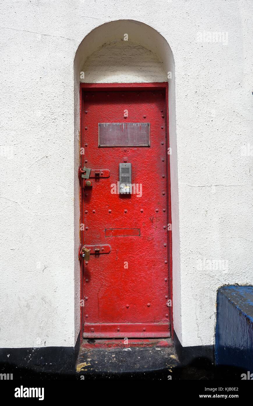 Ungewöhnlich geformte alten industriellen Gusseisen Tür mit einer modernen Sprechanlage. Stockfoto