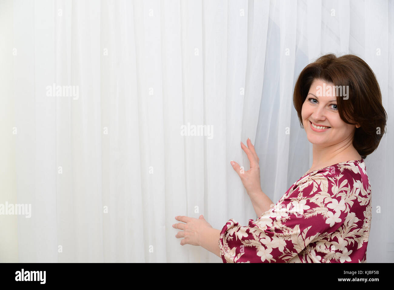 Die Frau steht in der Nähe von tulle weiße Vorhänge Stockfoto