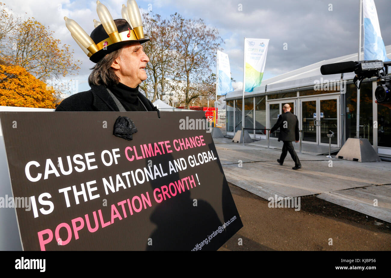 Bonn, Deutschland, 17. November 2017: Ein Mann in Kondom Hut hält einen Banner Warnung über bevölkerungswachstum vor Auf der COP 23 Klimawandel verleihen Stockfoto