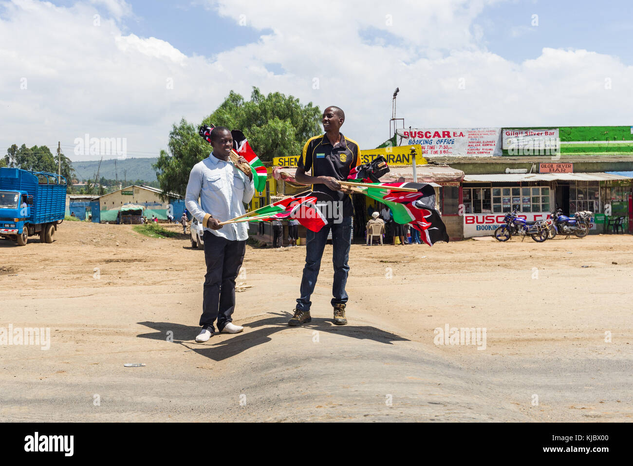Zwei afrikanische Männer verkaufen KENIANISCHEN Flaggen auf der Straße in einer kleinen Stadt, Kenia, Ostafrika Stockfoto