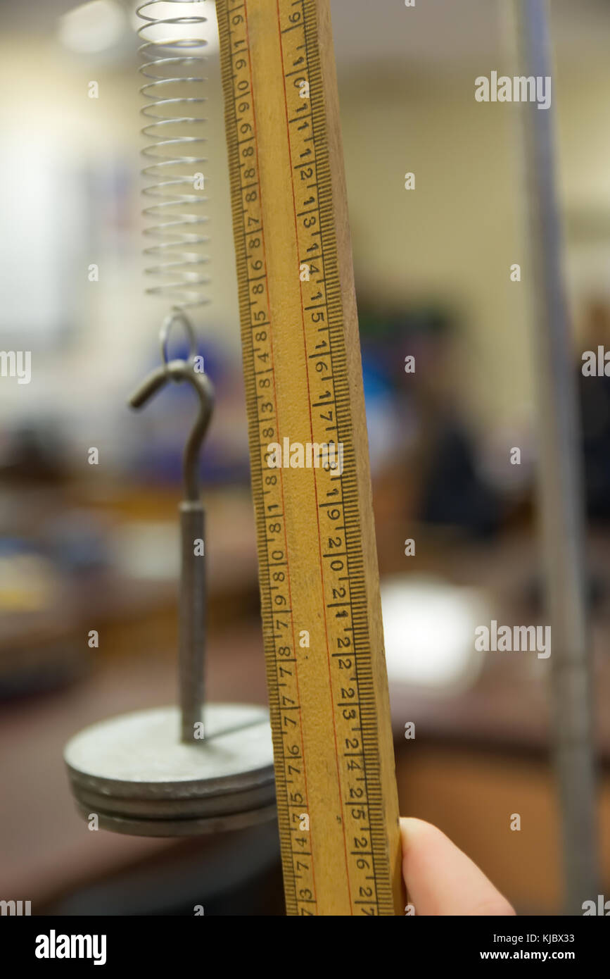 Schule Wissenschaft Kategorie mit der Schüler Hand mit einem meterstab die Länge der Erweiterung einer Feder mit Gewichten Massen für die hooke Gesetz Experiment zu messen Stockfoto