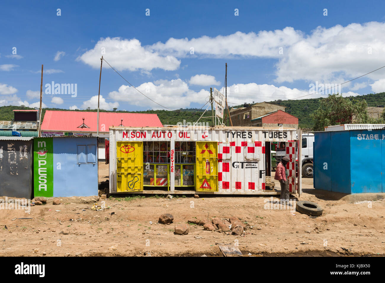 Ein afrikanischer Mann steht von einem Shop aus einer Wiederverwendet Shipping Container am Straßenrand, Kenia, Ostafrika Stockfoto