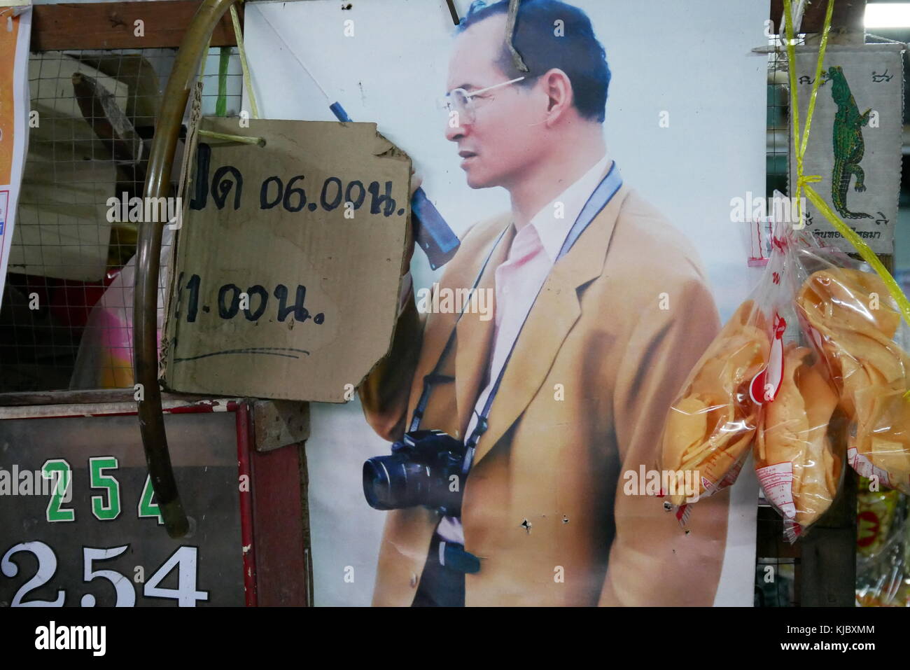 Ein Poster von Ende der thailändische König Bhumibol Adulyadej, Rama IX bekannt, mit einer Kamera um den Hals, in einem Markt, der entlang des Flusses in Bangkok, Thailand. Stockfoto