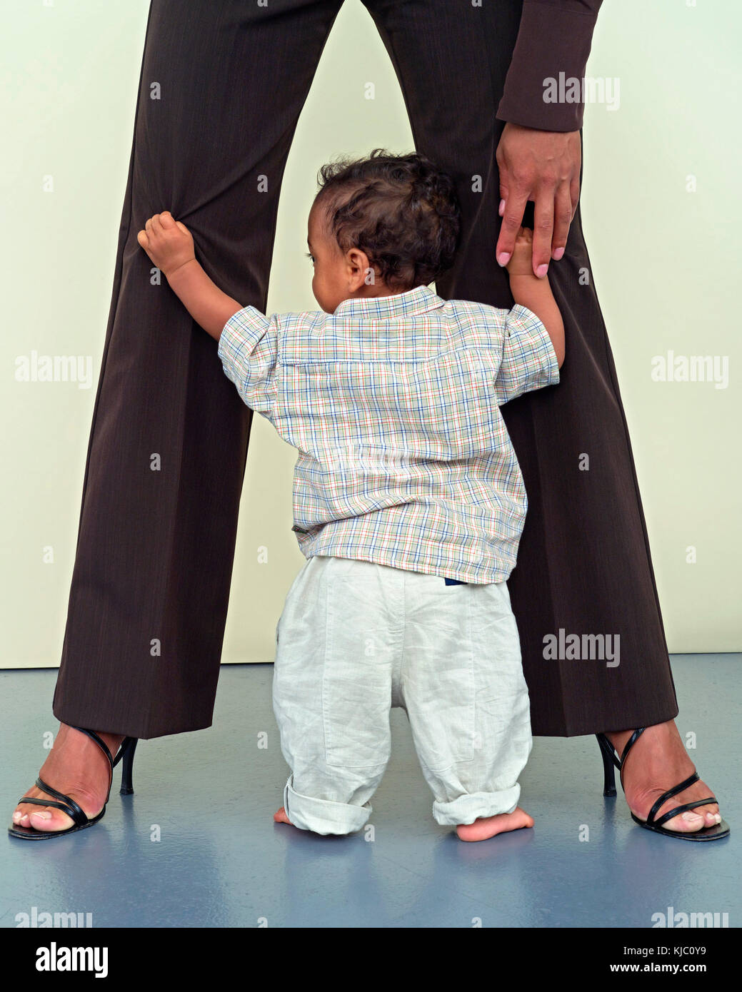 Baby Boy packte die Beine der Mutter Stockfoto