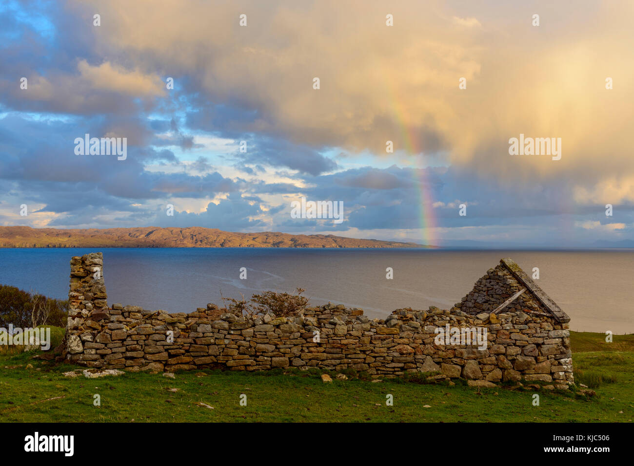 Überreste eines Steinhauses auf der Isle of Skye mit einem Regenbogen, der über der Küste in Schottland, Großbritannien, erscheint Stockfoto