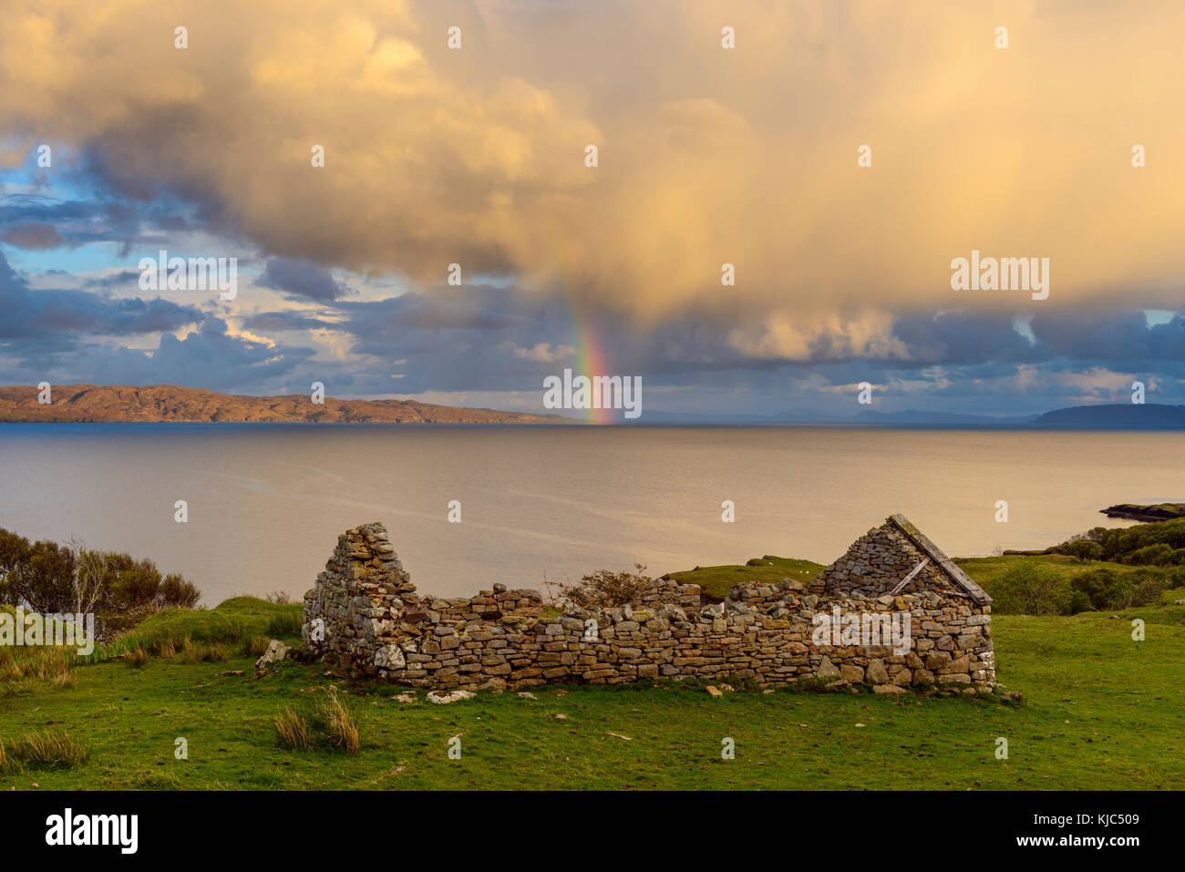 Überreste eines Steinhauses auf der Isle of Skye mit einem Regenbogen, der über der Küste in Schottland, Großbritannien, erscheint Stockfoto
