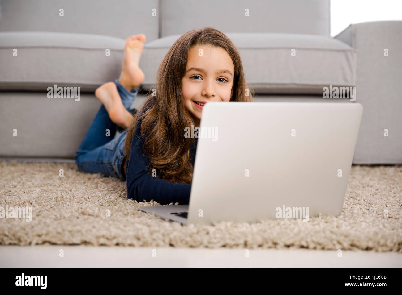 Fröhliches kleines Mädchen zu Hause arbeiten mit einem laptop Stockfoto
