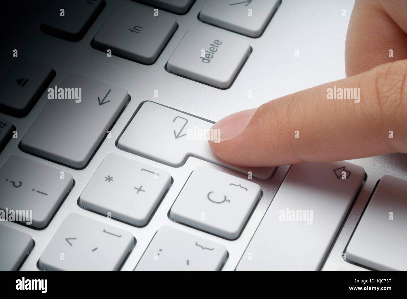 Zeigefinger drücken der ENTER-Taste an der Tastatur. Lichteffekt auf Tastatur verblassen. Konzept ein. Stockfoto