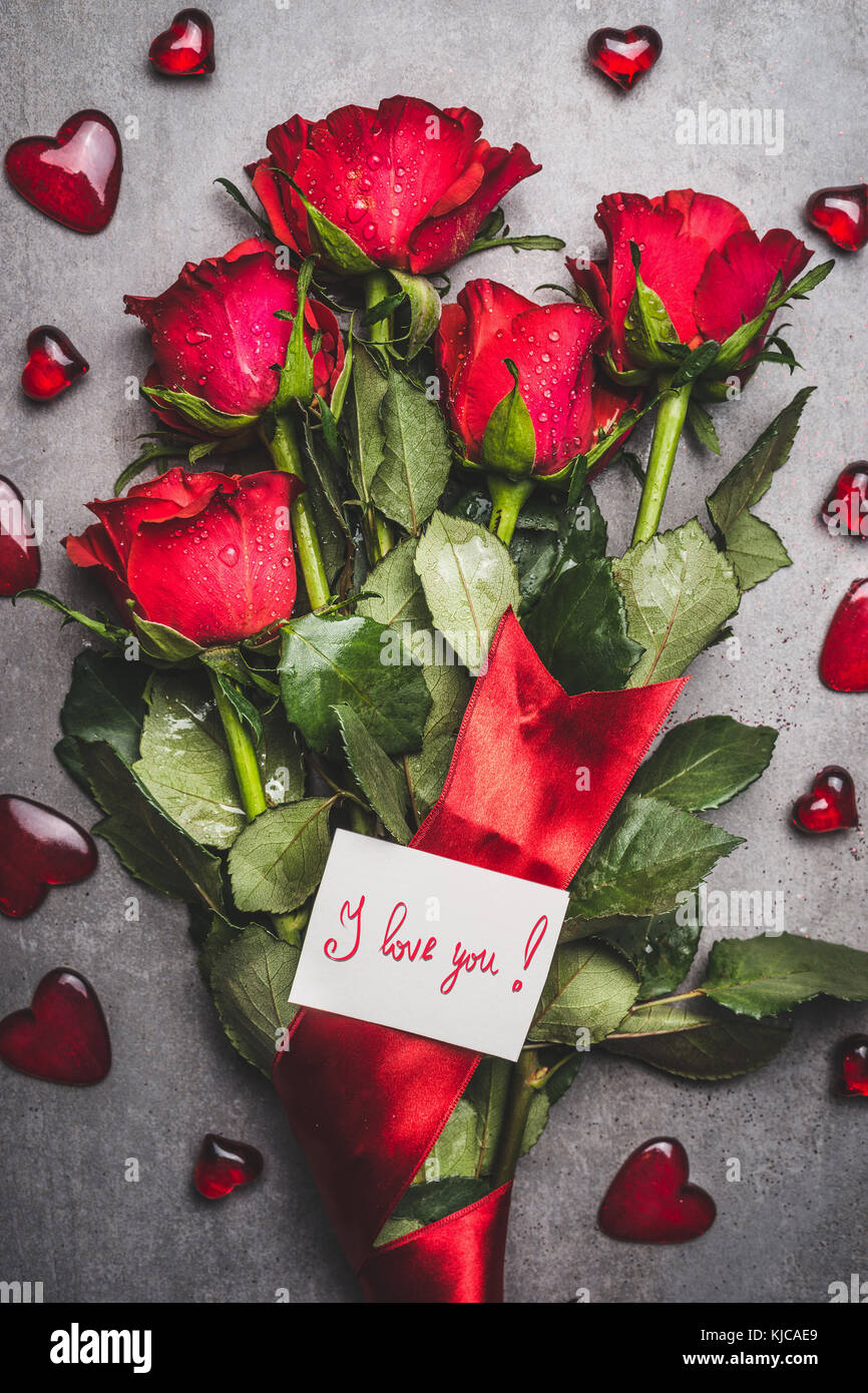 Grosse blumen strauß mit roten Rosen, Band, ich liebe sie Schriftzug Karte  und Herzen auf grauem Hintergrund, Ansicht von oben Stockfotografie - Alamy