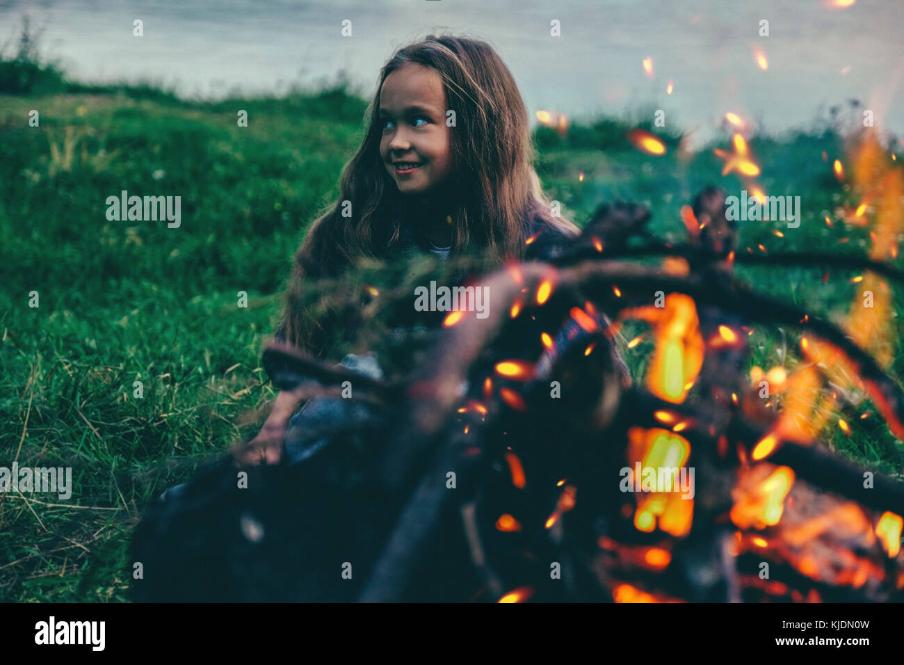 Kaukasische Mädchen sitzt in der Nähe von Lagerfeuer Stockfoto