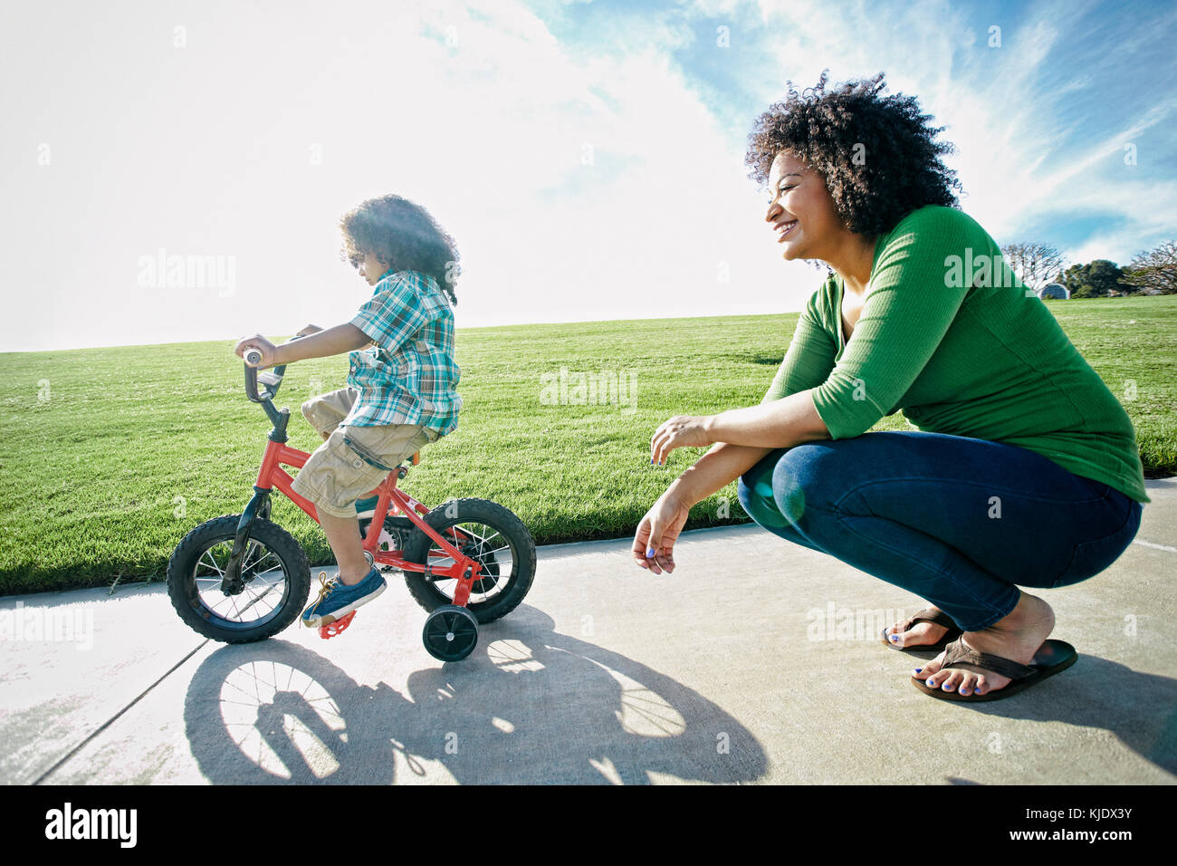 Mischlinge Mutter aufpassen Sohn fahren Fahrrad Stockfoto