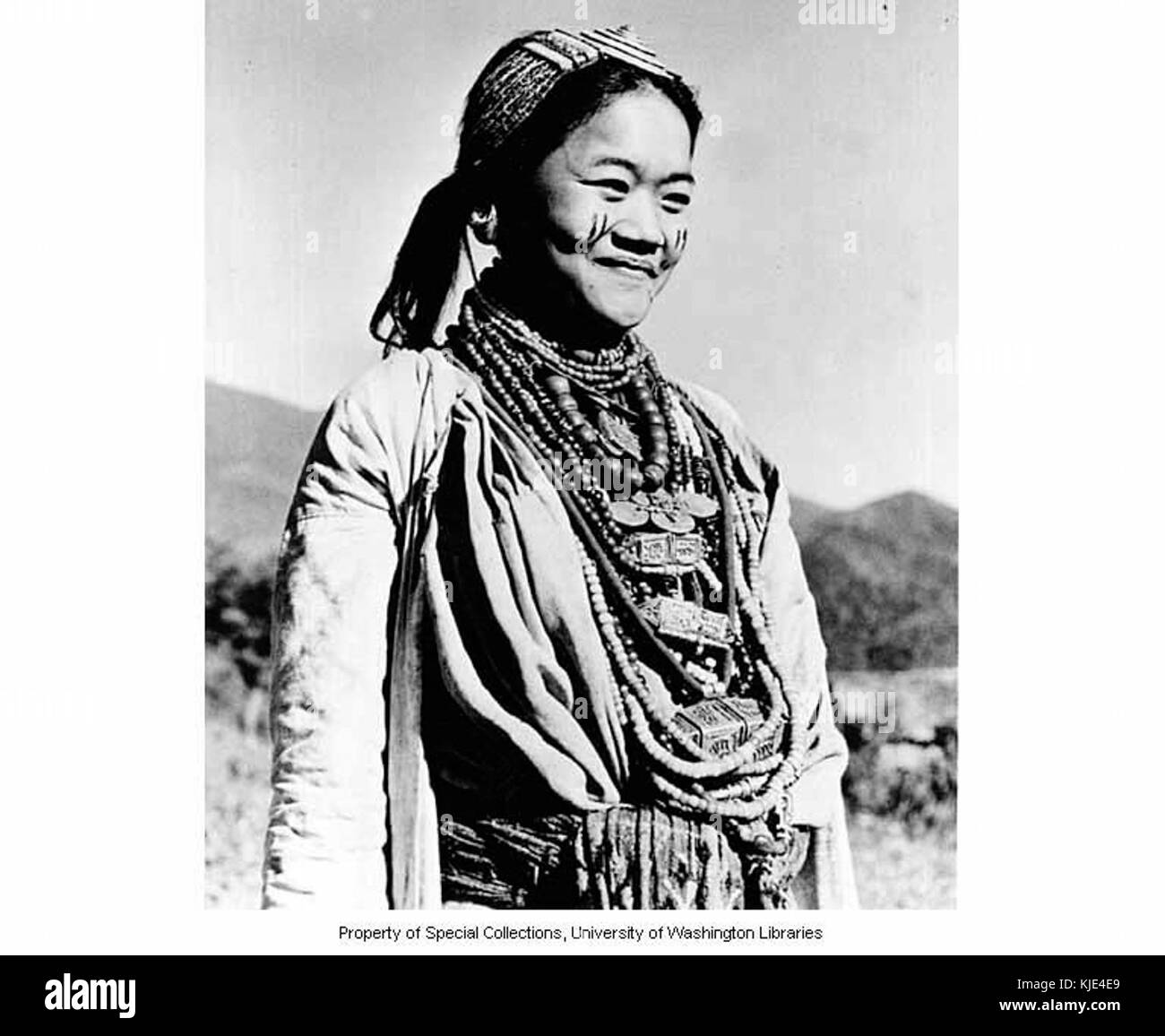 Eine Fotografie aus dem Jahr 1954 zeigt eine aka-Frau aus dem Dorf Jamiri in Indien, die mit traditioneller Gesichtsfarbe und tibetischen Ornamenten geschmückt ist, die die kulturellen Praktiken der Region widerspiegeln. Stockfoto