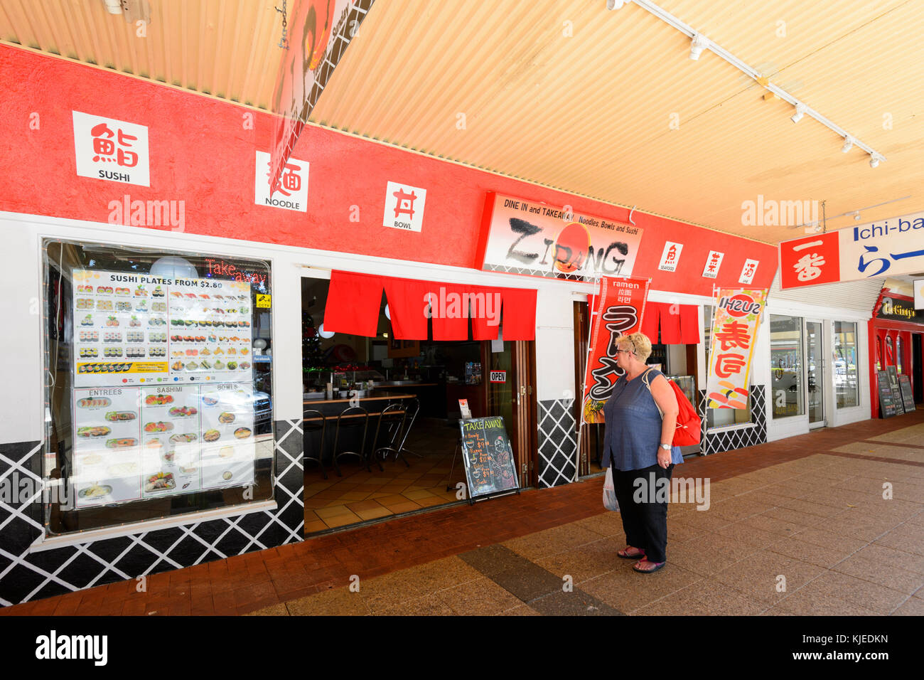 Reife Frau im Menü außerhalb Zipang, einem Japanischen Restaurant mit Sushi, Cairns, Far North Queensland, FNQ, QLD, Australien suchen Stockfoto