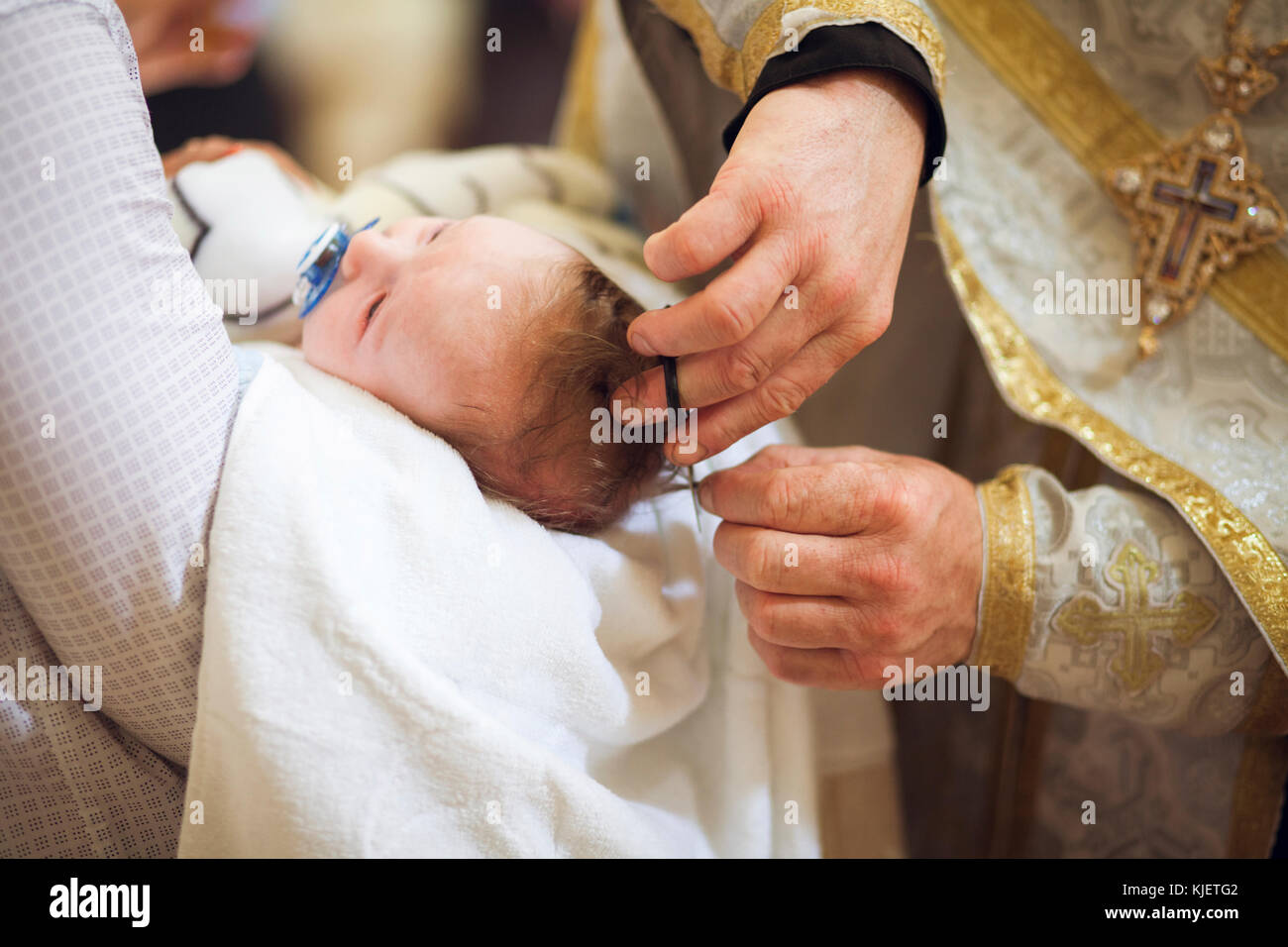 Priester Schneiden von baby girl Stockfoto