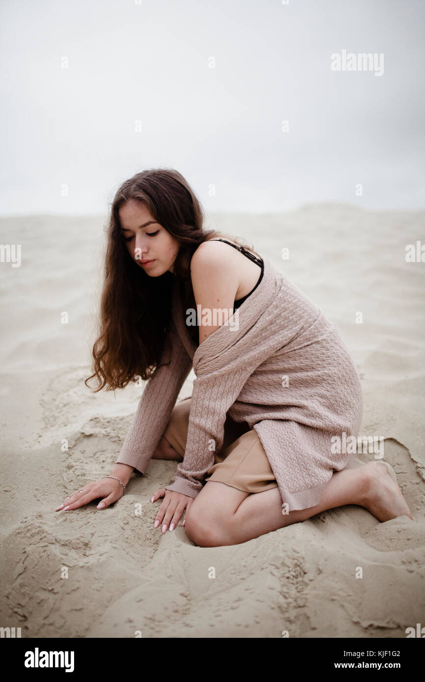 Kaukasische Frau in Sand kniende Stockfoto