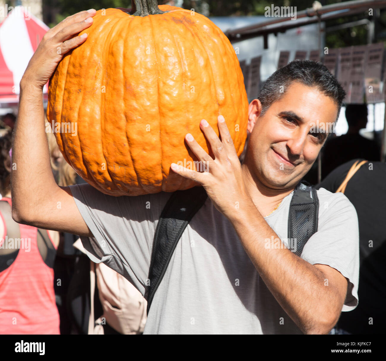 Mann, der große Kürbis für Halloween am Union Square Markt New York Stockfoto