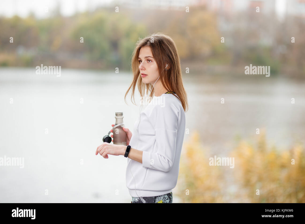 Junge Fitness Mädchen mit einer Flasche Wasser stehend Outdoor im City Park Stockfoto