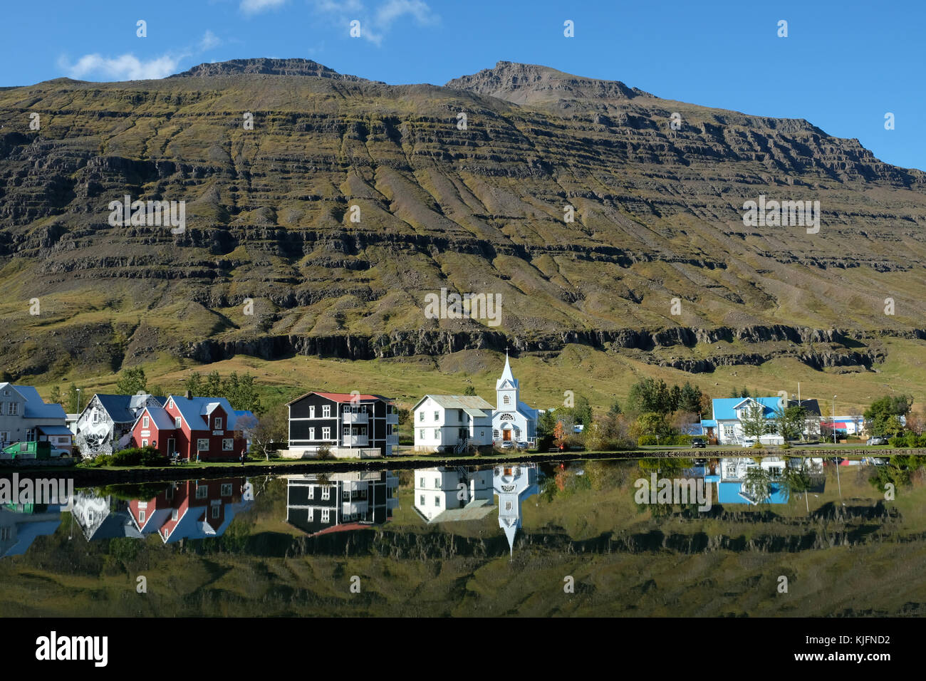 Seydisfjordur Stadthäuser spiegeln sich in stillem See mit Bergen im Hintergrund, Eastfjorde, Austurland, Ostisland, Skandinavien Stockfoto