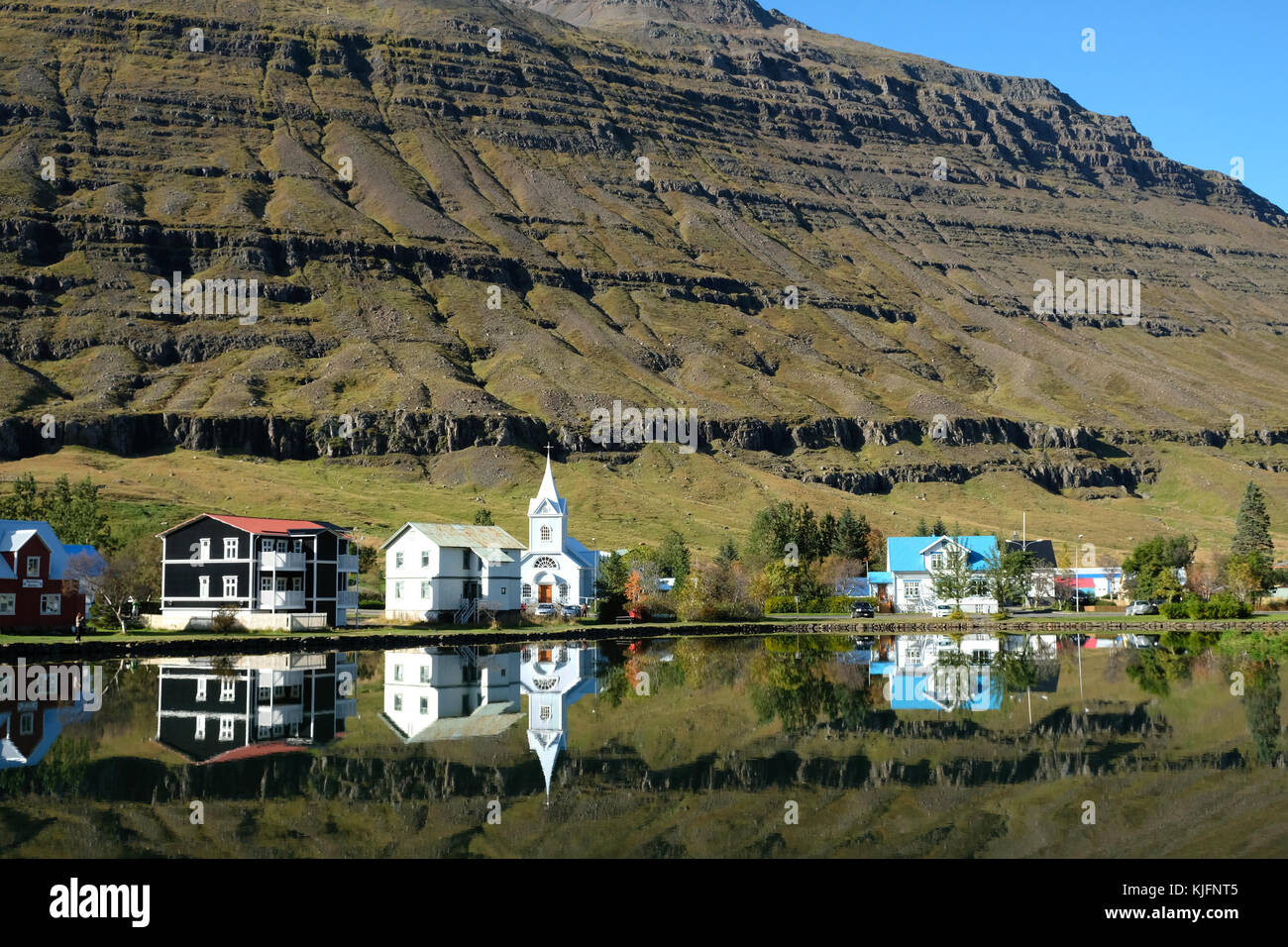 Seydisfjordur Stadthäuser spiegeln sich in stillem See mit Bergen im Hintergrund, Eastfjorde, Austurland, Ostisland, Skandinavien Stockfoto