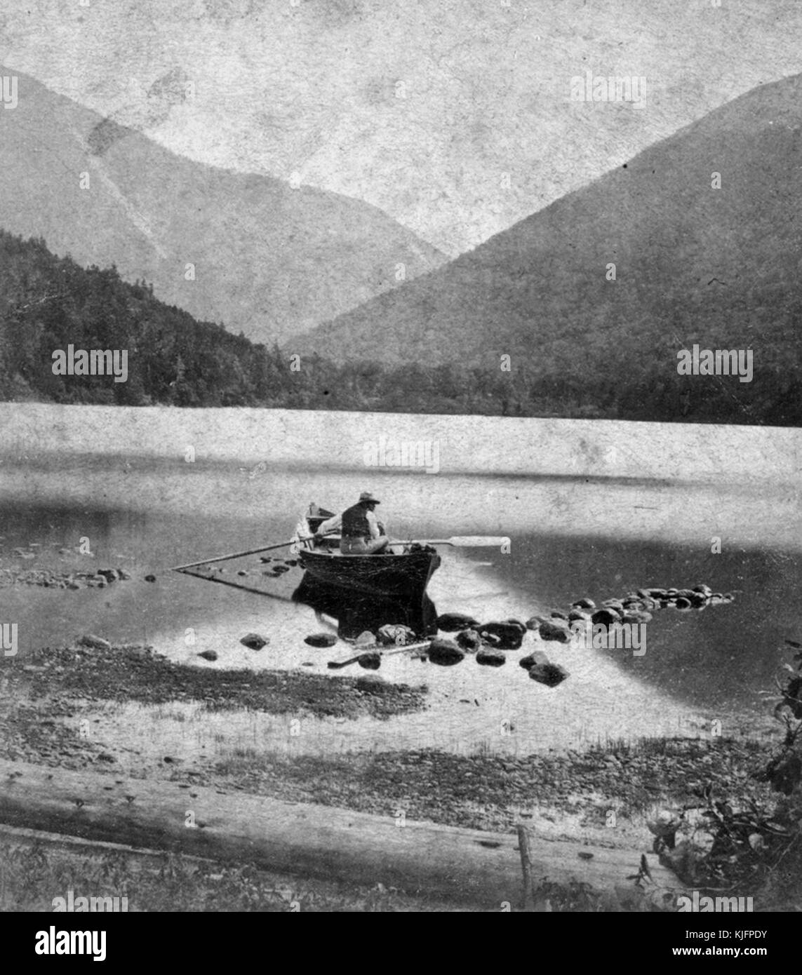 Foto eines Mannes in einem Kanu, im flachen Wasser, Berge im Hintergrund, mit dem Titel „Echo Lake and Franconia Notch, White Mountains“, veröffentlicht von Paul und Curtis, New Hampshire, 1865. Aus der New York Public Library. Stockfoto