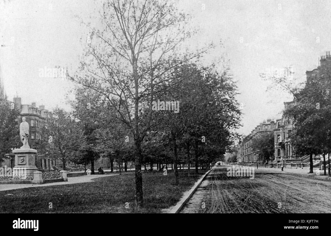 Ein Foto von Commonwealth Avenue, das Foto bietet einen Blick direkt auf die unbefestigte Straße, es ist eine geteilte Autobahn mit einem Gras bedeckten Einkaufszentrum in der Mitte, es verbindet den öffentlichen Garten mit den Fens, das Einkaufszentrum, das zwischen den Gassen verläuft enthält Gehwege, Bäume, Bänke, Und Statuen, Boston, Massachusetts, 1913. Stockfoto
