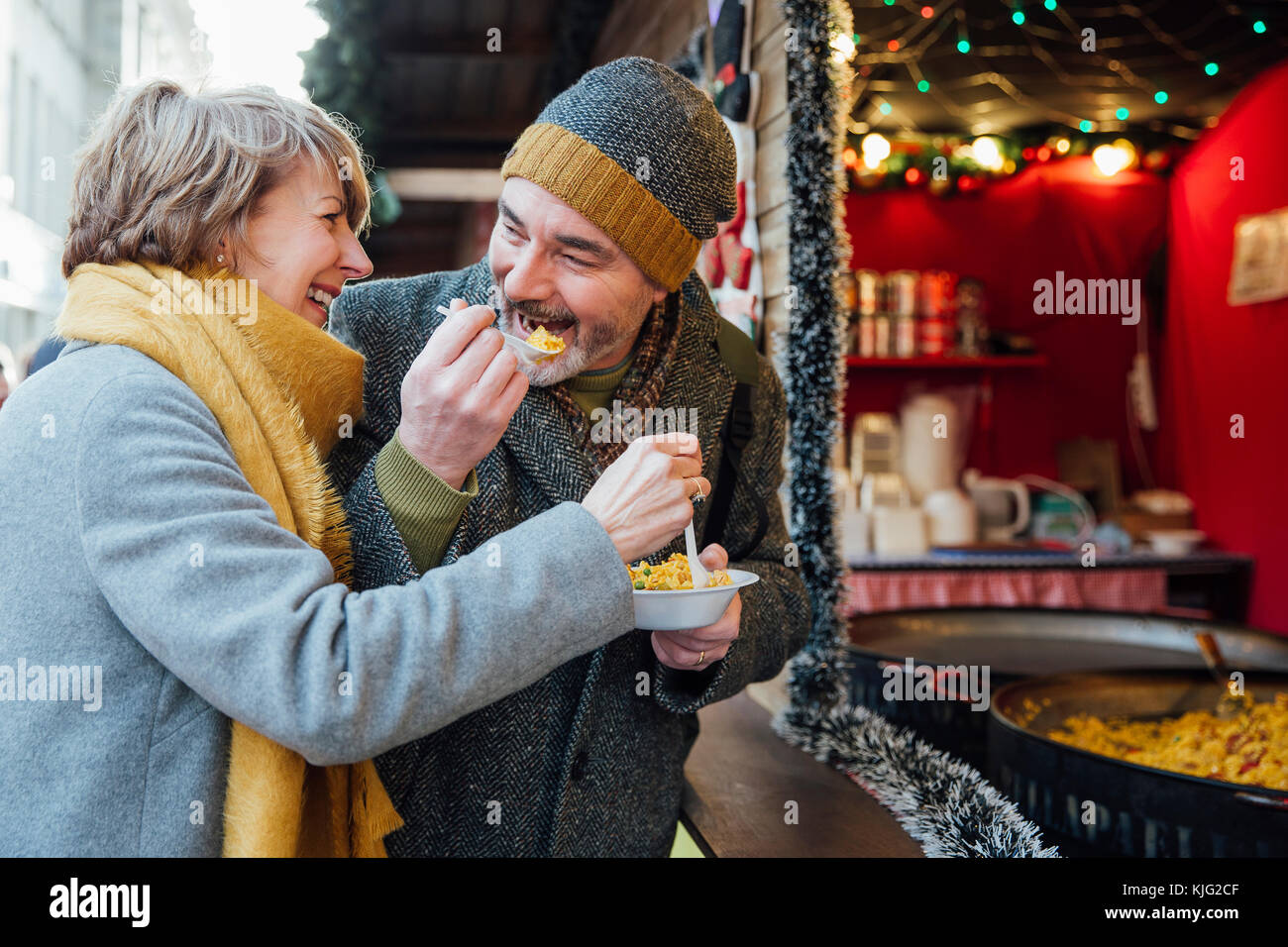 Reifes Paar genießen Sie einige Paella von einem Weihnachtsmarkt Abschaltdruck Stockfoto