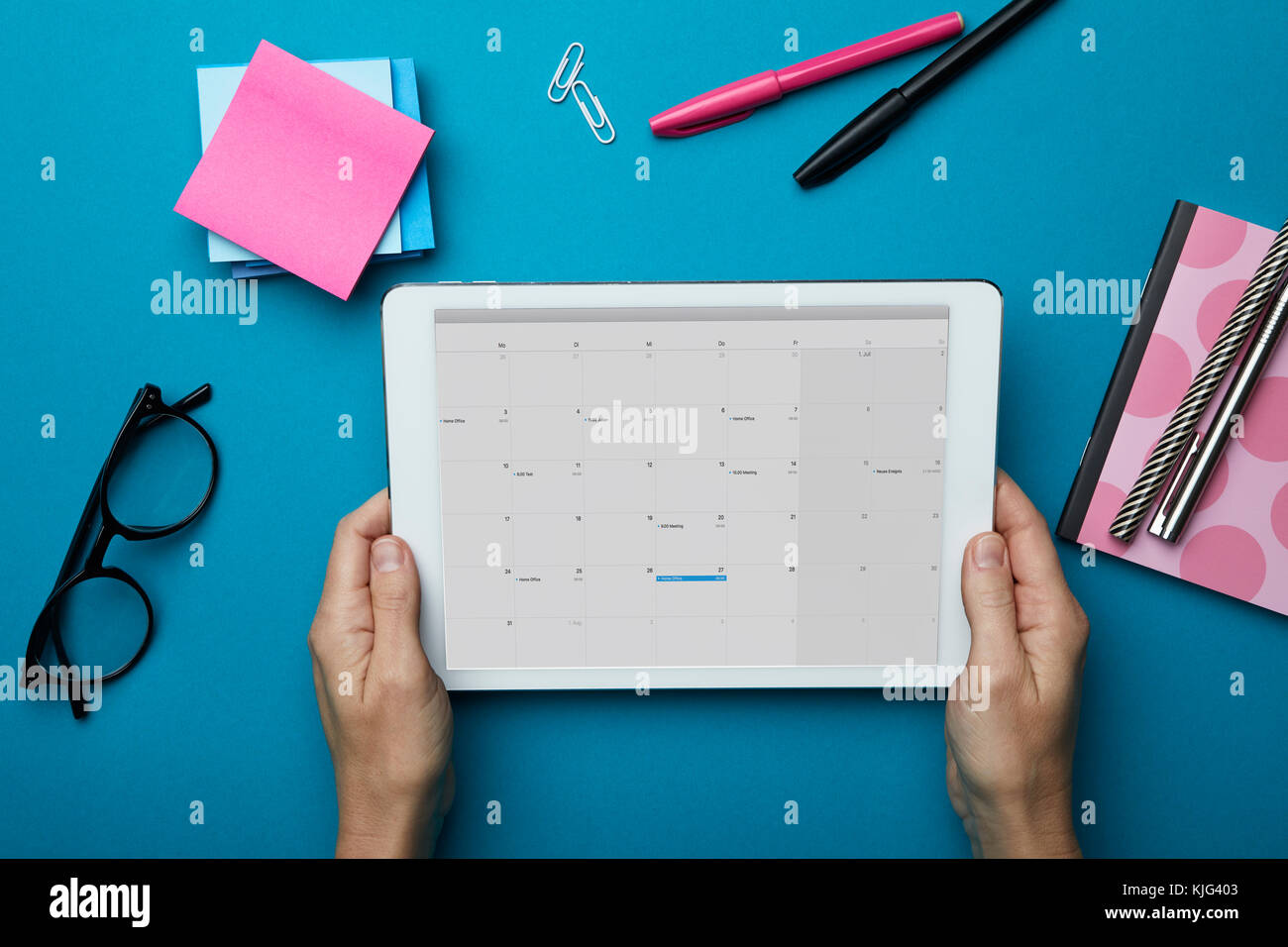 Blick von oben auf die Frau mit Tablet mit dem Kalender auf dem Schreibtisch Stockfoto